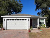 White house with a red door, two-car garage, and a brick paved driveway at 1493 Park Dr, Casselberry, FL 32707