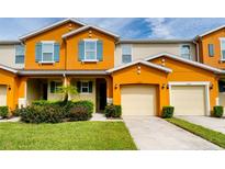 Inviting two-story townhome with orange exterior, two-car garage, and well-manicured lawn at 5107 Killarney Way, Kissimmee, FL 34746