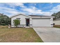 White house with black accents, two-car garage, and landscaped lawn at 608 Gila Dr, Kissimmee, FL 34759