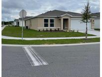 Tan one-story house with a white garage door and landscaped yard at 754 Hillview Loop, Haines City, FL 33844