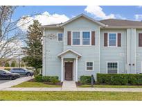 Two-story light-blue townhome with a front yard and walkway at 8984 Silver Pl, Kissimmee, FL 34747