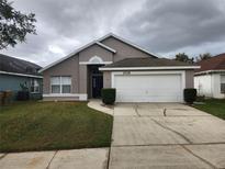 Front exterior of a single-story home with attached garage and landscaped yard at 2528 Chatham Cir, Kissimmee, FL 34746