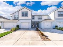 Charming two-story townhome with white siding, attached garage, and landscaped front yard at 3896 Grassland Dr, Orlando, FL 32824