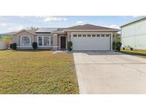 Front exterior of a single-story home with a two-car garage and solar panels at 622 Parakeet Ct, Kissimmee, FL 34759