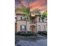 Two-story townhome with a balcony, palm trees, and landscaping at sunset at 733 Calabria Ave, Davenport, FL 33897