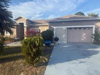 Tan one-story house with attached garage and landscaping at 1232 Apopka Ln, Kissimmee, FL 34759