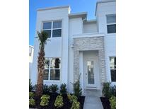 Modern white two-story home with gray stone accents and landscaped front yard at 1396 Peaceful Nature Way # 1396, Clermont, FL 34714