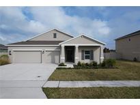 Tan house with gray roof, two-car garage, and landscaping at 420 Watusi Way, St Cloud, FL 34772