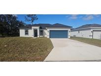 Single-story house with a teal garage door and landscaped lawn at 605 Raven Ct, Kissimmee, FL 34759