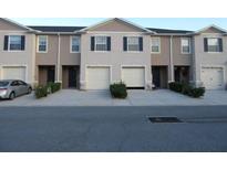 Three-unit townhome building with attached garages and landscaping at 1366 Yellow Finch Dr, Davenport, FL 33837