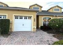 Exterior of a charming tan two-story home with a white garage door and paved driveway at 2642 Rutledge Ct, Winter Haven, FL 33884
