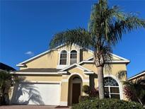 Beautiful two-story house with a yellow facade and palm trees at 437 Cadiz Loop, Davenport, FL 33837