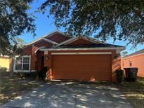 Orange one-story house with a two-car garage and a well-maintained lawn at 922 Sandy Ridge Drive Dr, Davenport, FL 33896