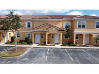 Two-story townhouses with Spanish-style architecture, featuring light-colored exteriors and lush landscaping at 2627 Bugatti Ct, Kissimmee, FL 34746