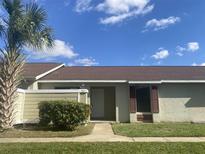 Exterior view of a light green house with a brown roof and neatly landscaped yard at 34 Pine Island Cir, Kissimmee, FL 34743