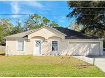 Beige house with a two-car garage and landscaped lawn at 796 Del Prado Dr, Kissimmee, FL 34758