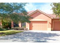 Attractive orange home with two-car garage, landscaping and paver driveway at 521 Milano Rd, Kissimmee, FL 34759