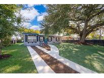 Newly renovated home with a landscaped yard and driveway at 7709 Ravenna Ave, Orlando, FL 32819