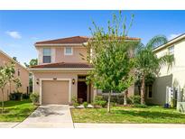 Two-story house with tan exterior, two-car garage, and landscaping at 8958 Sugar Palm Rd, Kissimmee, FL 34747