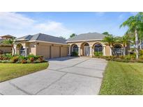 Beautiful tan three-car garage home with lush landscaping and a long driveway at 1280 Osprey Landing Dr, Lakeland, FL 33813