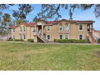 Tan two-story building with grassy lawn and trees at 2840 Osprey Cove Pl # 102, Kissimmee, FL 34746