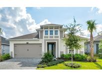 Two-story house with a gray and beige exterior, landscaped lawn, and a two-car garage at 128 Mosaic Blvd, Daytona Beach, FL 32124