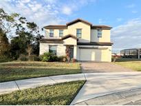 Two-story house with light beige walls, brown roof, and a two car garage at 210 Kenny Blvd, Haines City, FL 33844