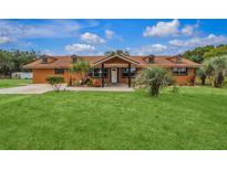 One-story home with brown exterior and a well-maintained lawn at 22134 Obrien Rd, Howey In The Hills, FL 34737