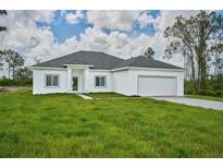 Single story home with a two-car garage and grassy yard at 7811 Red Grange Blvd, Indian Lake Estates, FL 33855