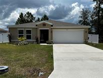 Single story home with two car garage and landscaped lawn at 319 Hibiscus Dr, Kissimmee, FL 34759