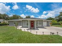 Charming one-story home with a red door and well-manicured lawn at 1075 8Th Nw St, Winter Haven, FL 33881