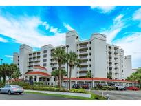 White building with red accents, palm trees, and parking lot at 1 John Anderson Dr # 604, Ormond Beach, FL 32176