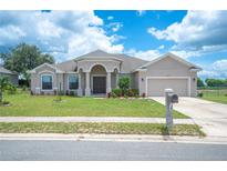 Single-story home with tan exterior, arched entryway, and two-car garage at 4046 Dinner Lake Way, Lake Wales, FL 33859