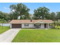 Brick ranch home with a brown door, attached garage, and a well-manicured lawn at 4314 Ridge Rd, Lakeland, FL 33811