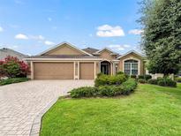 House exterior featuring a three-car garage and manicured lawn at 2316 Midnight Pass Ct, The Villages, FL 32162