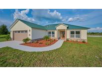 Single-story home with green metal roof and attached garage at 7031 Red Grange Boulevard Ave, Indian Lake Estates, FL 33855
