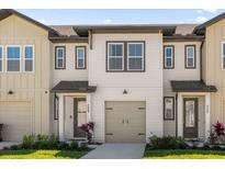 Two-story townhome with light beige siding, brown accents, and a two-car garage at 709 Longboat Dr, Davenport, FL 33896