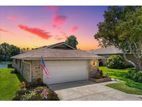 Brick ranch home with attached garage, American flag, and landscaping at sunset at 696 Caribbean Dr, Lakeland, FL 33803