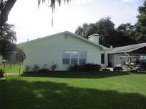 Light green single story home with large windows and a golf cart at 10742 W Beach Pkwy, Lake Wales, FL 33898