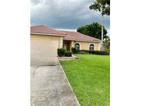 Single-story home with a red tile roof and a large grassy yard at 417 Bay Leaf Dr, Kissimmee, FL 34759