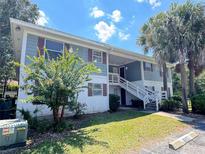 Exterior view of a light-blue two-story building with stairs and surrounding landscaping at 8206 Fairways Cir # B204, Ocala, FL 34472