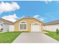 Tan house with white garage door and green lawn at 2443 Parsons Pond Cir, Kissimmee, FL 34743