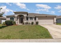 House exterior showcasing a one-story home with a two-car garage and well-manicured lawn at 4728 Magnolia Preserve Ave, Winter Haven, FL 33880