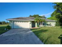 Front view of a single-story house with a driveway and landscaped yard at 6556 Red Grange Blvd, Indian Lake Estates, FL 33855