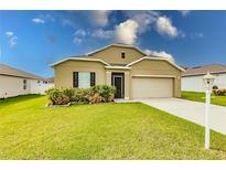 Tan one-story house with a two-car garage and landscaped yard at 6048 Forest Ridge Ln, Winter Haven, FL 33881