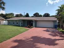 Single-story house with a teal exterior, attached garage and a brick driveway at 44 Sandra Dr, Ormond Beach, FL 32176