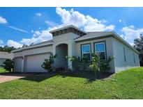 Two-car garage, one-story home with landscaping at 5522 Windsong Oak Dr, Leesburg, FL 34748