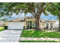 Single story home with a large tree, manicured lawn and a white garage door at 107 Needlewood Loop, Debary, FL 32713