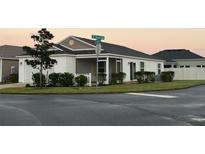 White house with gray roof, screened porch, and well-manicured lawn at 4415 Casey Ct, The Villages, FL 32163