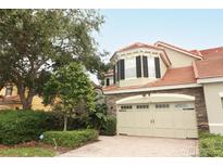 Two-story townhome with a tan facade and two-car garage at 7126 Regina Way, Orlando, FL 32819